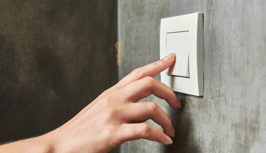 Illustrazione di una persona mentre spegne la luce (Canva FOTO) - energycue.it